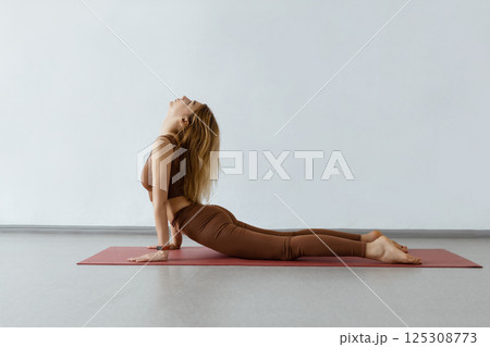 An attractive girl sits on a yoga mat. Slim body and health care.UP DOG , URDHVA MUKHA SVANASANA An attractive girl sits on a yoga mat. Slim body and health care.UP DOG , URDHVA MUKHA SVANASANA 125308773