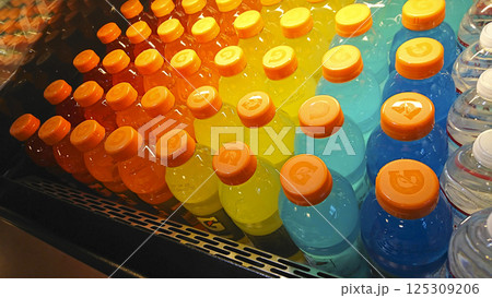 ストアの冷蔵棚に虹のようなグラデーションを描き陳列された色とりどりのスポーツドリンクのペットボトル 125309206