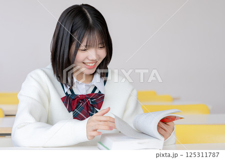 笑顔で教材を見る女子生徒 笑顔で教材を見る女子生徒 125311787