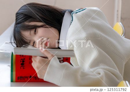 寝ながら赤本を読む女子生徒 125311792
