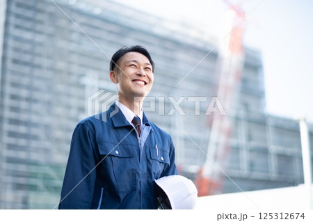 大規模な工事現場の前を歩く業者の男性 大規模な工事現場の前を歩く業者の男性 125312674