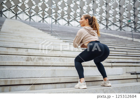Young woman practices yoga with in modern outdoor setting during afternoon. People, fitness concept 125312684