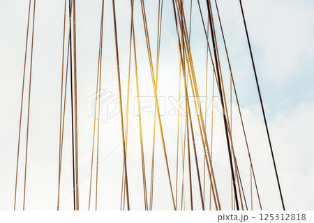 Rope cables against cloudy sky create industrial abstract pattern, background 125312818