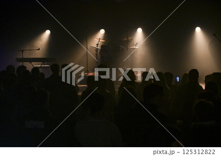 Energetic concert atmosphere with excited audience waiting for performance in a dimly lit venue 125312822
