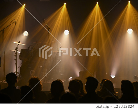Musicians prepare for a lively concert with colorful lighting and engaged audience silhouetted Musicians prepare for a lively concert with colorful lighting and engaged audience silhouetted 125312824