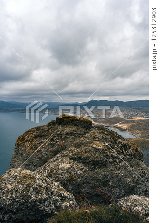 Scenic view from a rocky outcrop overlooking a coastal landscape under cloudy skies Scenic view from a rocky outcrop overlooking a coastal landscape under cloudy skies 125312903