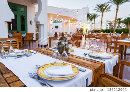 Elegant outdoor dining setup in a lush tropical setting during sunset 125312962