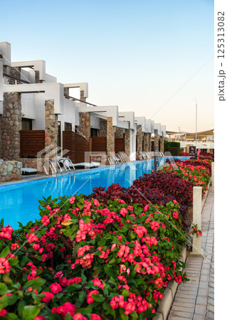 Luxurious resort pool surrounded by vibrant flowers in a serene setting at sunset Luxurious resort pool surrounded by vibrant flowers in a serene setting at sunset 125313082