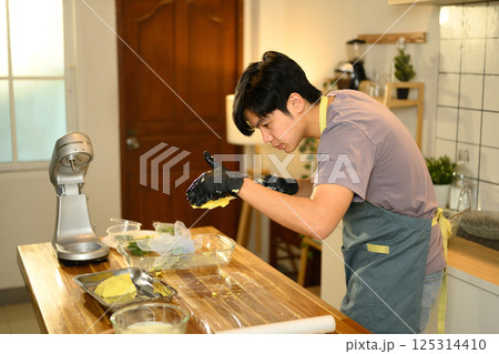 Asian man shaping compound butter by hand in a cozy kitchen Asian man shaping compound butter by hand in a cozy kitchen 125314410