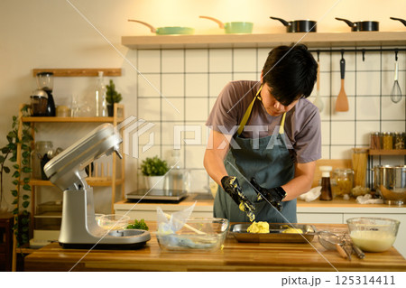 Man mixing herbs and butter on wooden counter in warm light 125314411