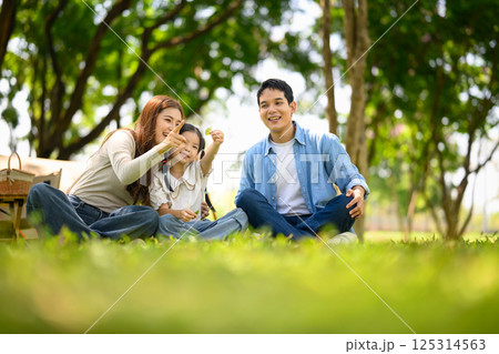 Happy family enjoying time together in nature during a sunny day picnic 125314563