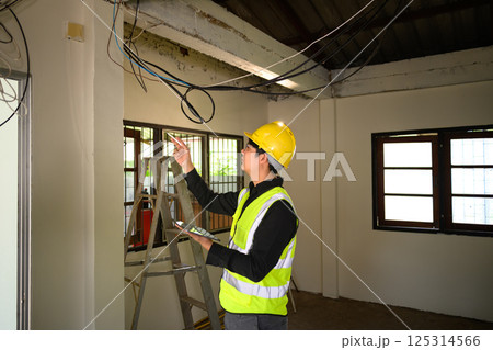 Male construction supervisor examining electrical cables at renovation site Male construction supervisor examining electrical cables at renovation site 125314566