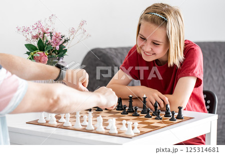 Thoughtful, Cute Little Girl Plays Chess With Father, Drawing Lots For The Right To Make The First Move 125314681