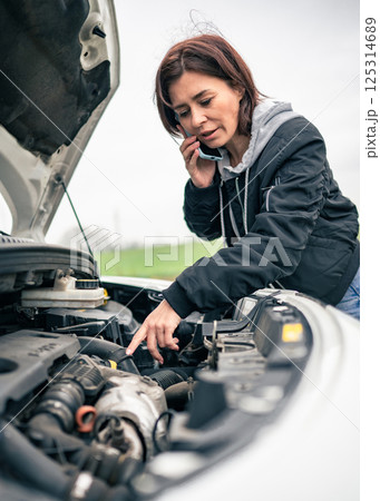 Female Driver With Broken Car On A Road Talks On The Phone With Service Female Driver With Broken Car On A Road Talks On The Phone With Service 125314689