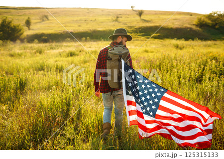 4th of July. American Flag.Patriotic holiday. Traveler with the flag of America. Beautiful sunset light. American style. 4th of July. American Flag.Patriotic holiday. Traveler with the flag of America. Beautiful sunset light. American style. 125315133