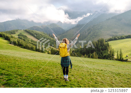 Female tourist with yellow backpack on top of mountain enjoying view of valley. Hiking concept. Female tourist with yellow backpack on top of mountain enjoying view of valley. Hiking concept. 125315897