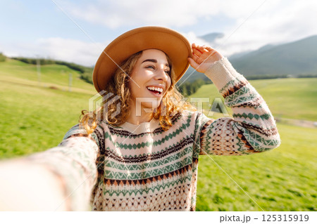 Close-up of a happy woman taking a selfie while hiking. Nature, adventure concept. Active lifestyle. 125315919