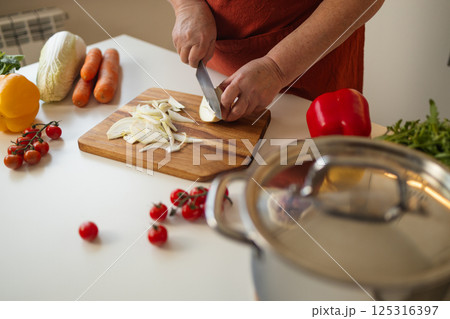 Person Slicing Onion in Kitchen for Cooking 125316397