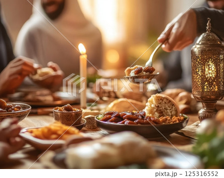 Muslim family breaking fast with dates and food at sunset in warm decorated modern home 125316552