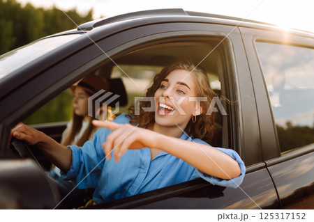 Two young women on car trip having fun. Lifestyle, travel, tourism, nature, active life. 125317152