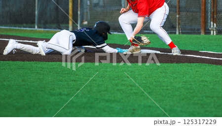 Baseball player diving back to first base on a pickoff attempt Baseball player diving back to first base on a pickoff attempt 125317229