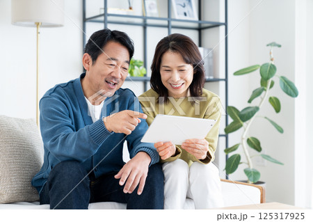 リビングでタブレットを見るミドルの夫婦 125317925