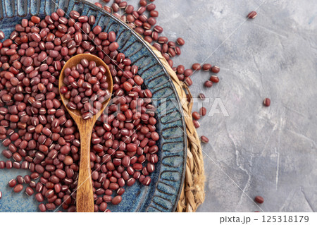 Blue plate full of dried red azuki beans with a wooden spoon top view. Vegetarian protein source Blue plate full of dried red azuki beans with a wooden spoon top view. Vegetarian protein source 125318179