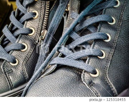 Detailed close-up view of navy blue laced shoes showcasing craftsmanship and design in a modern urban setting Detailed close-up view of navy blue laced shoes showcasing craftsmanship and design in a modern urban setting 125318455