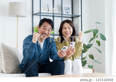 リビングでスマホを見るミドルの夫婦 125318568