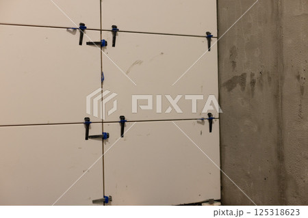 Wall leveling system. Instalation of ceramic tile in a bathroom on plastered walls. Wall leveling system. Instalation of ceramic tile in a bathroom on plastered walls. 125318623