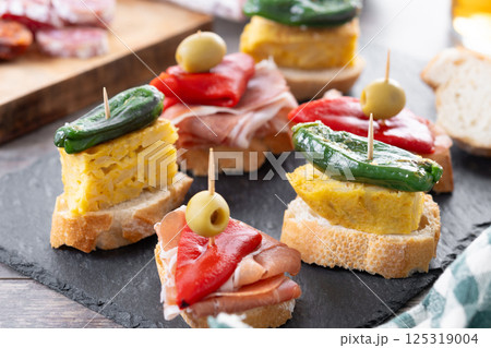 Traditional Spanish pintxos on wooden table Traditional Spanish pintxos on wooden table 125319004