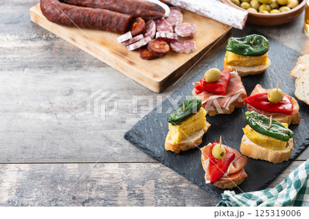Traditional Spanish pintxos on wooden table Traditional Spanish pintxos on wooden table 125319006