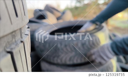 Car Tire Rubber Dump. Pile of Old Car Tyres Storage. man throws used car tires into a landfill. Car tires for recycling. Environment Disaster Concept. Car Tire Rubber Dump. Pile of Old Car Tyres Storage. man throws used car tires into a landfill. Car tires for recycling. Environment Disaster Concept. 125319735