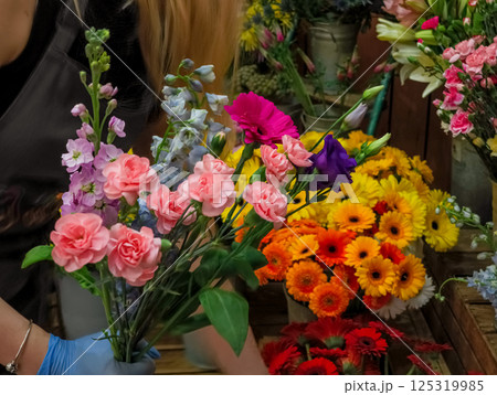 Florist arranging pink carnations and colorful flowers in bouquet Florist arranging pink carnations and colorful flowers in bouquet 125319985