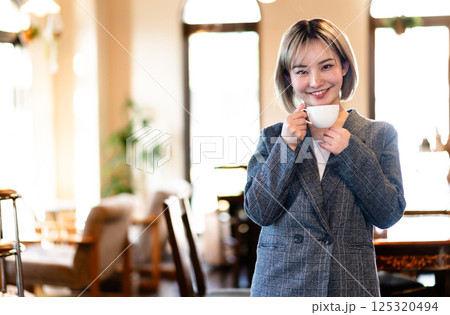コーヒーカップを持つ笑顔の若い女性 125320494
