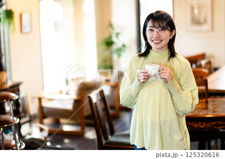 コーヒーカップを持つ笑顔の女性 125320616
