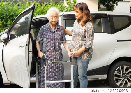 Caregiver help Asian elderly woman disability patient get in her car. 125320968