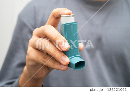 Asthma and chronic obstructive pulmonary disease COPD, Asian young man using metered dose inhaler MDI. 125321061