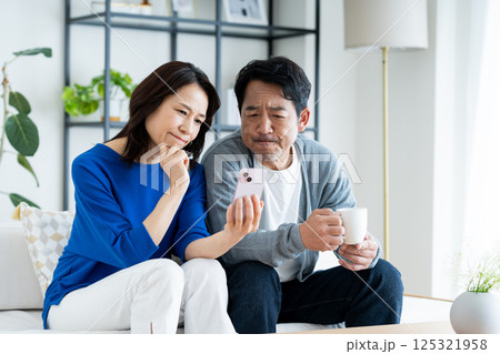 リビングでスマホを見るミドルの夫婦 リビングでスマホを見るミドルの夫婦 125321958