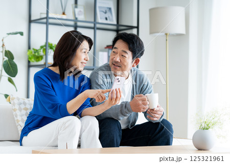 リビングでスマホを見るミドルの夫婦 125321961