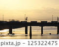 夕暮れの川辺を走る列車と車のシルエット 125322475