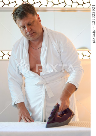 An adult man does housework, irons washed clothes An adult man does housework, irons washed clothes 125322921