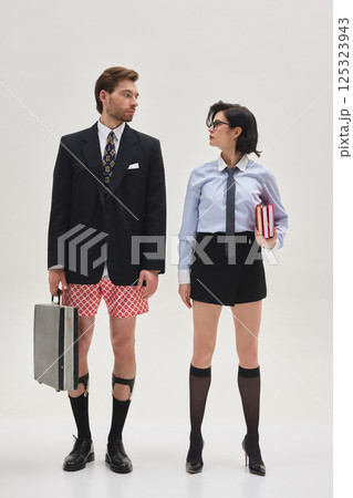 Man in blazer and underwear standing next to woman in formal shirt and tie, both staring at each other in surreal office scene. 125323943