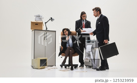 Three office workers gathered around printer, woman yelling on phone while others present documents in messy white studio scene. Three office workers gathered around printer, woman yelling on phone while others present documents in messy white studio scene. 125323959