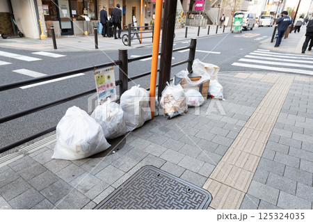 歩道に捨てられている可燃ごみ 白い袋に入れて置かれている家庭ごみ 歩道に捨てられている可燃ごみ 白い袋に入れて置かれている家庭ごみ 125324035