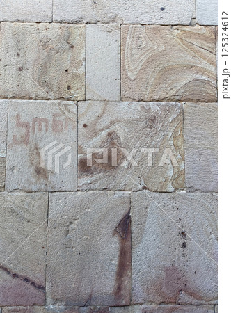 Beige sandstone church wall with large, textured bricks. Historic architecture detail, ideal as a natural stone background or rustic texture for design and creative projects. 125324612