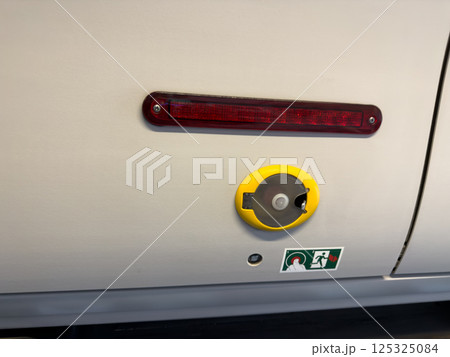 Emergency door release mechanism in public transport vehicle, featuring a sealed handle and clear instruction icon for safe and fast evacuation procedures 125325084