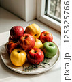 Red apples in drops of water on a white plate 125325766