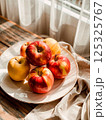 Red apples in drops of water on a white plate 125325767