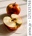 sliced green apple in drops of water on a white plate 125325768